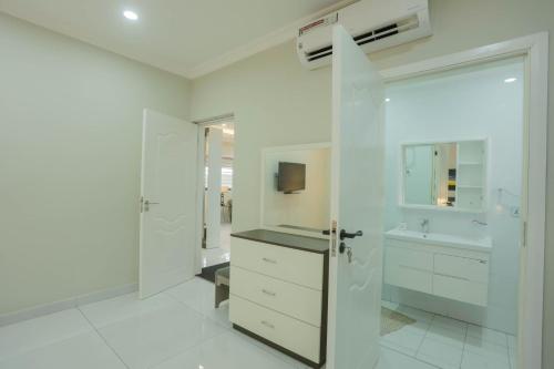 Baño blanco con lavabo y espejo en Accra Luxury Apartments @ Silicon Square en Accra