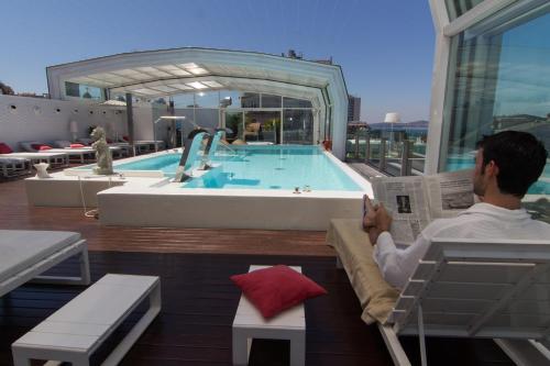 a man reading a newspaper next to a swimming pool at Gran Hotel Nagari Boutique & Spa in Vigo