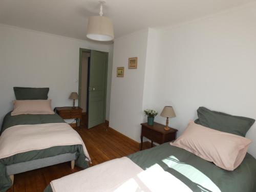 Habitación con 2 camas, paredes blancas y suelo de madera. en Chez Elise et Thomas en Le Mage