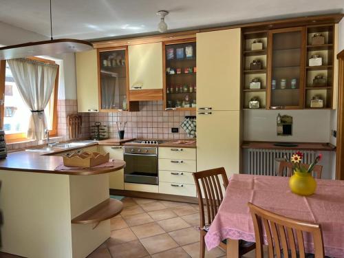 a kitchen with wooden cabinets and a table with chairs at Appartamento Fiore dell'Alpe in Premadio