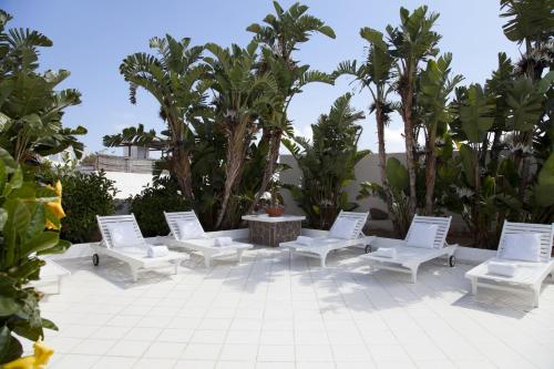 a patio area with chairs, tables and umbrellas at Hotel Lisca Bianca in Panarea