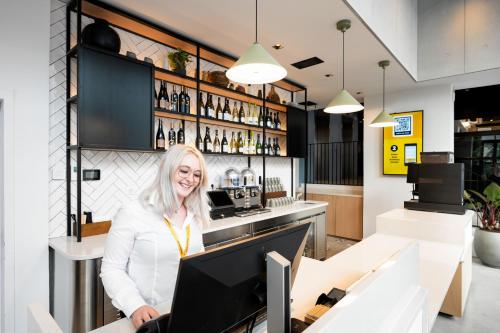 a woman standing at a counter in a bar at Staycity Aparthotels Paris La Defense in Courbevoie
