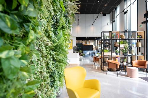 a room with a green wall with chairs and tables at Staycity Aparthotels Paris La Defense in Courbevoie