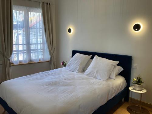 - une chambre avec un lit doté de draps blancs et une fenêtre dans l'établissement Maison de charme au cœur de la baie de Somme, à Saint-Valery-sur-Somme