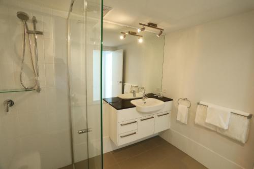 uma casa de banho com um lavatório e uma cabina de duche em vidro. em Q Resorts Paddington em Townsville
