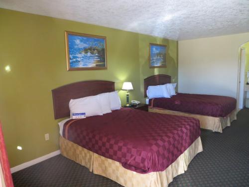 2 Betten in einem Hotelzimmer mit grünen Wänden in der Unterkunft Americas Best Value Inn & Suites Hempstead in Hempstead