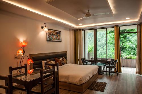 德拉敦Haut Monde Hill Stream Resort and Spa的一间卧室，配有一张床、一张书桌和一张桌子