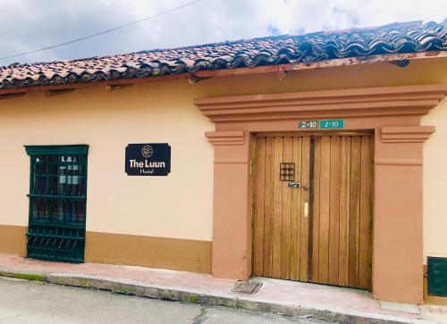 een gebouw met een houten deur en een bord erop bij The Luun Hostel in Bogota