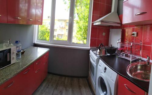 a kitchen with red cabinets and a washing machine at Apartment near Farkhadskiy bazar in Tashkent