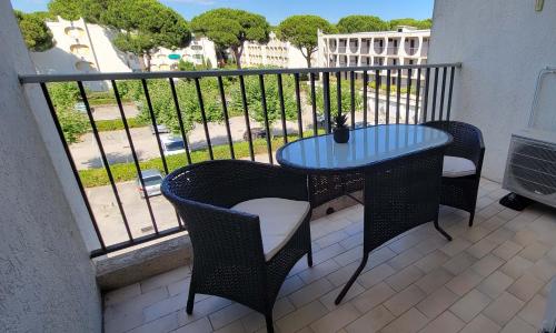 d'une table et de chaises sur un balcon avec vue sur la rue. dans l'établissement Studio proche centre et plage avec clim et parking, à La Grande Motte