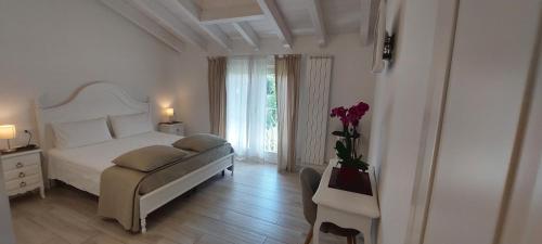 a white bedroom with a bed and a vase of flowers at Casa Speri in Peschiera del Garda