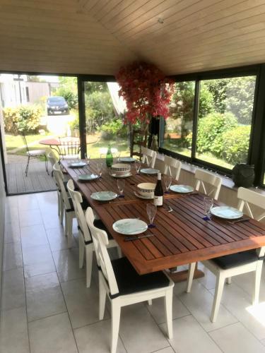 - une table et des chaises en bois dans une chambre avec fenêtres dans l'établissement Kêr Korrigan - Villa familiale, à Saint-Gildas-de-Rhuys
