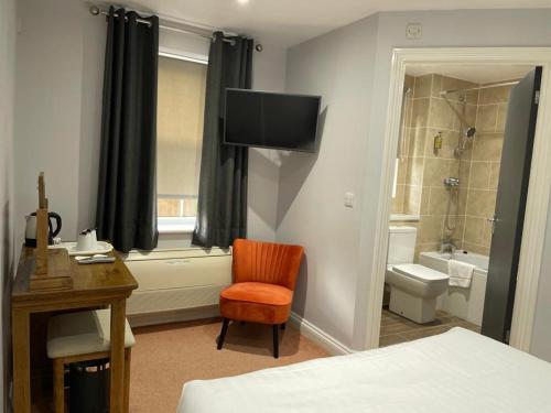 a bedroom with a bed and a chair and a bathroom at Best Western Claydon Hotel in Ipswich