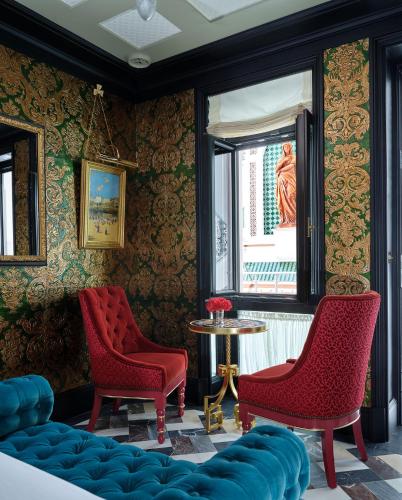 a room with two red chairs and a table at Hotel Boutique Triana House in Seville