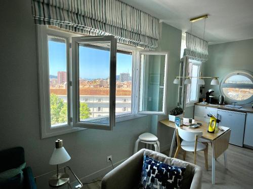 a living room with a couch and two windows at Vue sur rade appartement élégant vaste climatisé étage élevé ascenseur proche parking et toutes commodités au cœur du Toulon historique in Toulon
