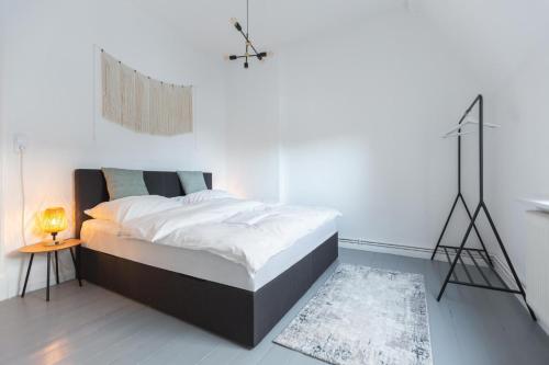 a white bedroom with a large bed and a lamp at Bheaven I Skandi Premium Apartment in Bremerhaven