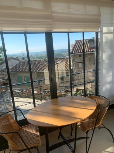 a table and chairs in a room with a large window at Le haut plan VÉZÉNOBRES in Vézénobres