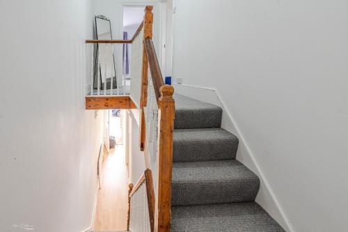 a staircase in a home with a wooden hand rail at Cheerful 4 bedrooms home 8 mn to train station in Plumstead