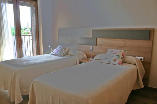 two beds in a hotel room with a window at Los Casares in Riaño