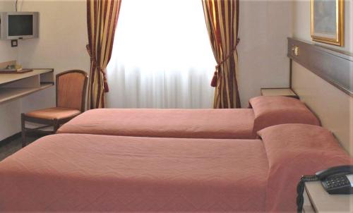 a hotel room with two beds and a desk at Bes Hotel Papa San Pellegrino Terme in San Pellegrino Terme