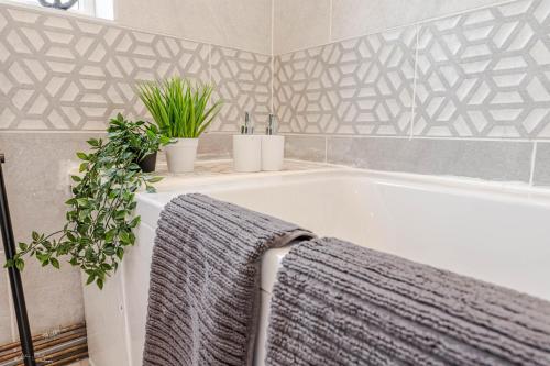 a bathroom with a bath tub with two potted plants at Cheerful 4 bedrooms home 8 mn to train station in Plumstead