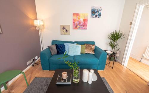 a living room with a blue couch and a table at Cheerful 4 bedrooms home 8 mn to train station in Plumstead