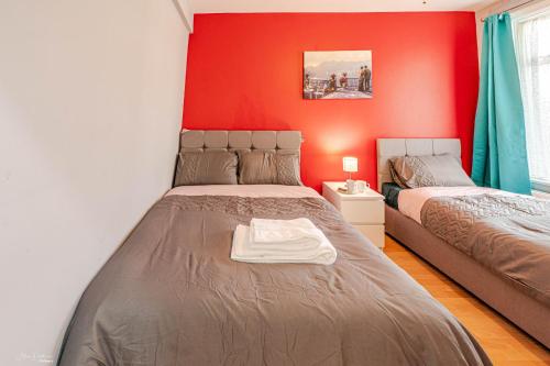 a bedroom with two beds and a red wall at Cheerful 4 bedrooms home 8 mn to train station in Plumstead