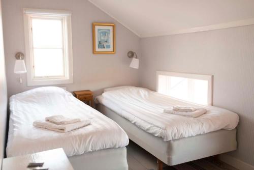 two beds in a room with white sheets and towels at Prästgårdens Pensionat in Mollösund