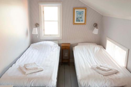 two beds in a room with white sheets and a window at Prästgårdens Pensionat in Mollösund