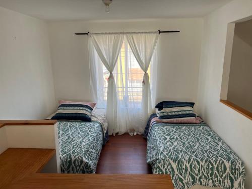two beds in a room with a window at Apart Hotel Chillan - Full House 2 Ohiggins - Empresas - Factura in Chillán