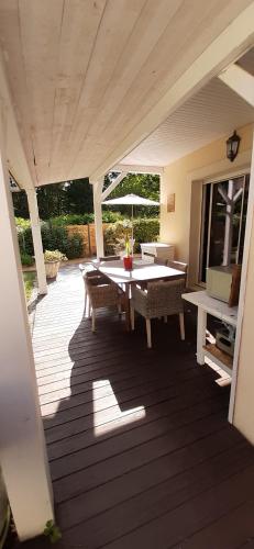 un patio avec une table, des chaises et un parasol dans l'établissement La Tanière, à Brette-les-Pins