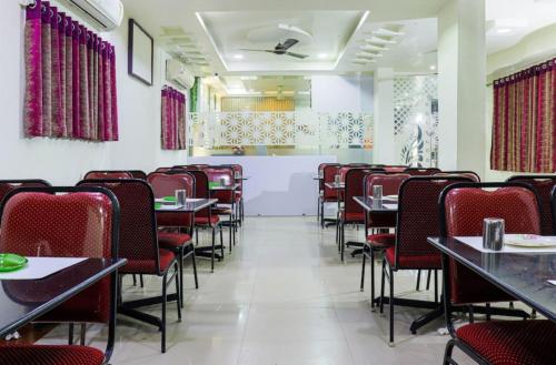 a dining room with tables and red chairs at Hotel Menaka in Vijayawāda