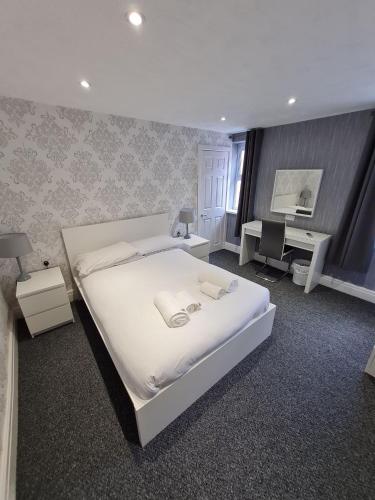 a bedroom with a large white bed and a desk at Queens Plaza Hotel in Blackpool