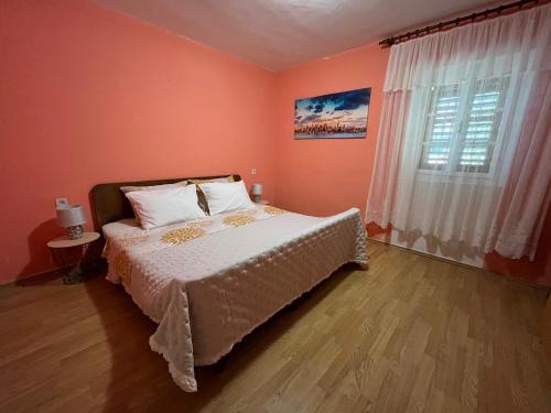 um quarto com uma cama com paredes cor de laranja e uma janela em Apartman Mateo em Lozovac