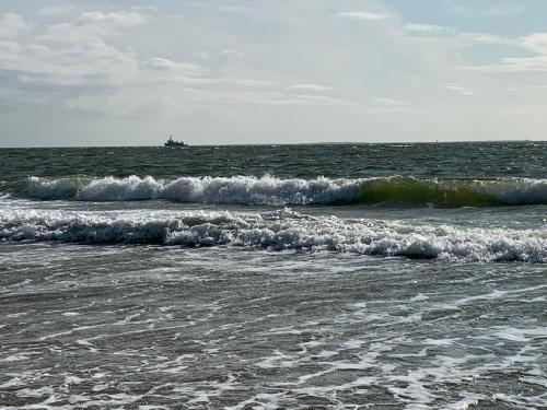 a group of waves in the ocean with a ship in the distance at Lüttje Najade in Borkum