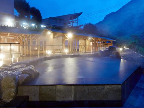 a hot tub in front of a building at night at Okudogo Ichiyunomori in Matsuyama