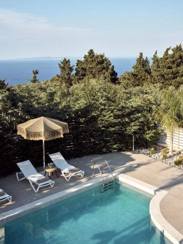 a swimming pool with two chairs and an umbrella at Conte Nobile Villa, a Rejuvenating Retreat, By ThinkVilla in Vasilikos