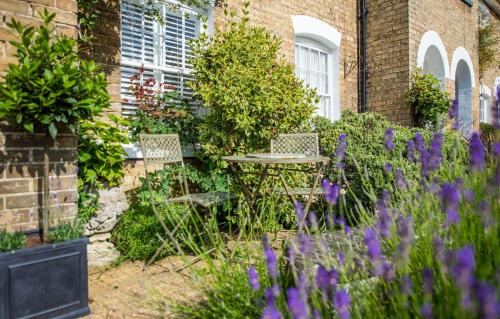 a garden with a table and chairs and purple flowers at 3 Church Walk in Long Melford in Long Melford