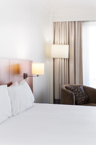 a bedroom with a bed and a chair and a window at Majestic Roof Garden Hotel in Adelaide