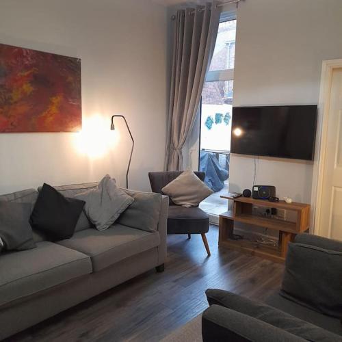 a living room with a couch and a tv at Cosy Jesmond 3 bed apartment - fantastic location in Jesmond