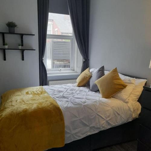 a bed with yellow pillows in a bedroom with a window at Cosy Jesmond 3 bed apartment - fantastic location in Jesmond