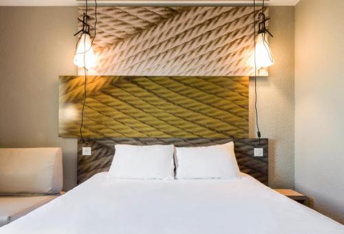 a bedroom with a large bed with two pillows at ibis Issy les Moulineaux "Val de Seine" in Issy-les-Moulineaux