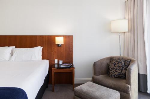 a hotel room with a bed and a chair at Majestic Roof Garden Hotel in Adelaide