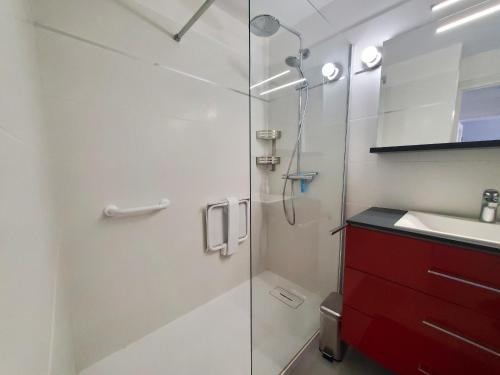 La salle de bains est pourvue d'une douche et d'une armoire rouge. dans l'établissement MIOUGRANO 2 Pieces Climatise 40m2 Piscine Parking, à Fréjus