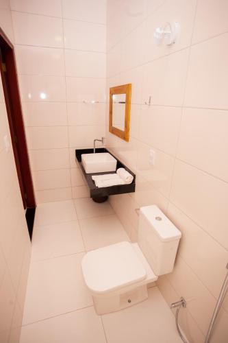 a white bathroom with a toilet and a sink at Pousada Lírio Trancoso in Trancoso