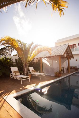 a swimming pool with two chairs and a gazebo at Pousada Lírio Trancoso in Trancoso