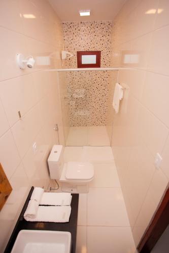a white bathroom with a sink and a toilet at Pousada Lírio Trancoso in Trancoso