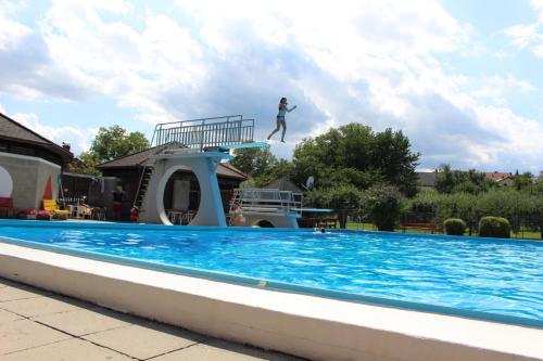 a person jumping off a diving board over a swimming pool at Blockhaus Chalet mit beheizbarem Badefass und Infrarotsauna auf der Terrasse in Oberschützen