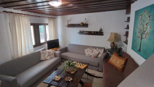 een woonkamer met een bank en een tafel bij VillaTzer - Traditional house with fireplace and garden in Tzermiádon