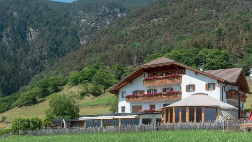 a large white building with a fence in front of a mountain at Hotel-Chalet Pennhof in Barbiano